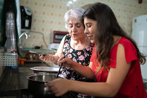 Care aid and older woman cooking